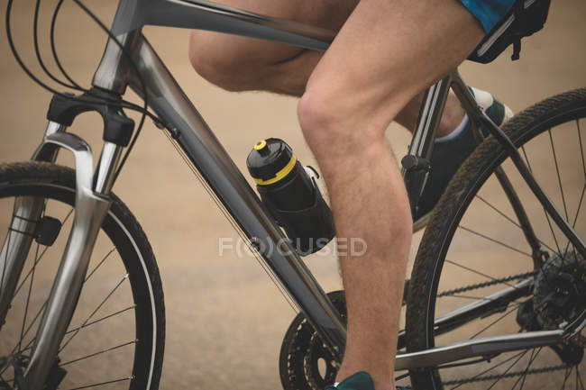 Niedriger Abschnitt des Mannes Radfahren am Strand während der Übung — Stockfoto