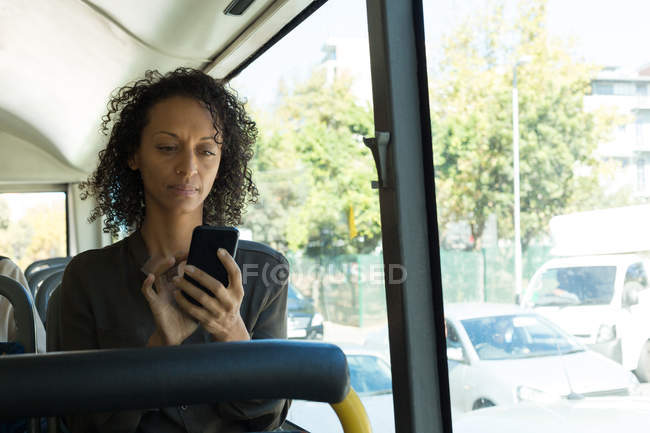 Femme utilisant un téléphone portable tout en voyageant dans le bus — Photo de stock