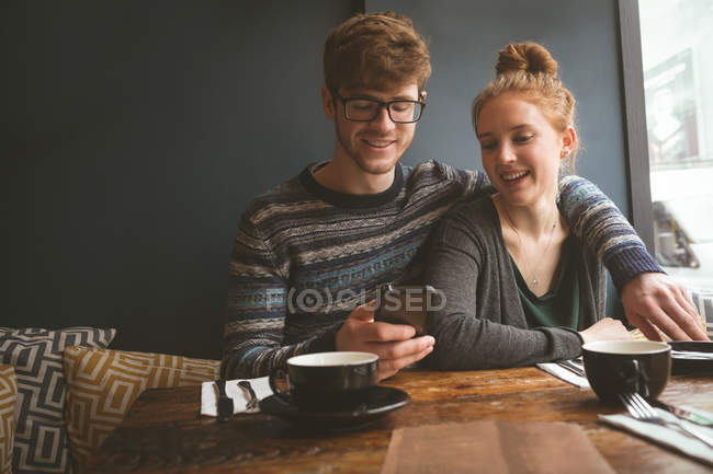 Casal jovem usando telefone celular no café — Fotografia de Stock