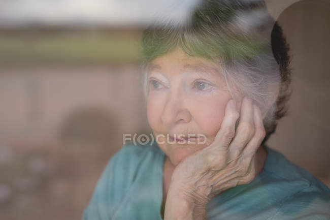 Ragionevole donna anziana guardando fuori dalla finestra — Foto stock
