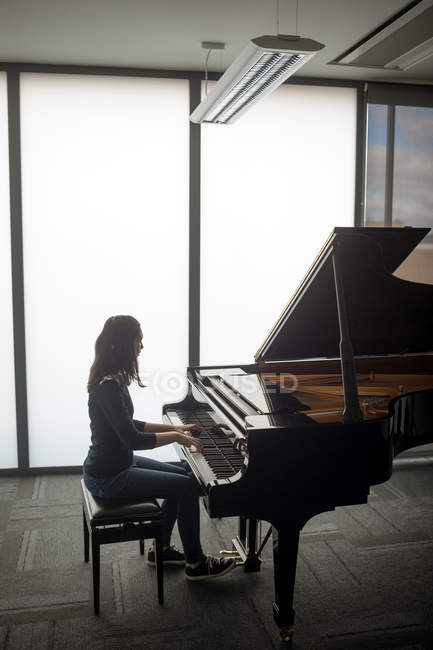 Vista lateral de la colegiala tocando el piano en la escuela de música - foto de stock
