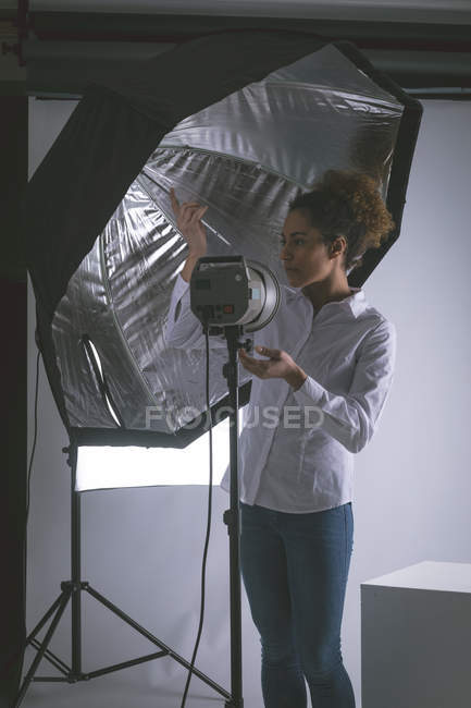 Fotógrafo feminino ajustando luzes estroboscópicas no estúdio de fotografia — Fotografia de Stock