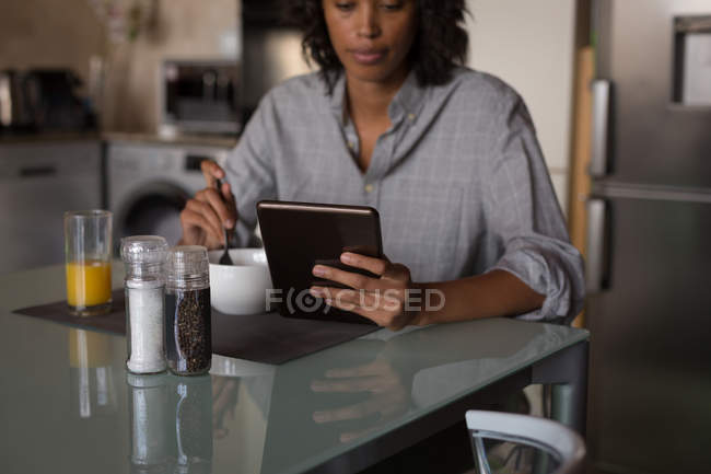 Frau frühstückt zu Hause mit Laptop — Stockfoto