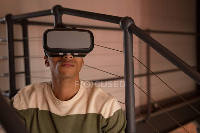 Человек, использующий гарнитуру виртуальной реальности на лестнице дома — стоковое фото