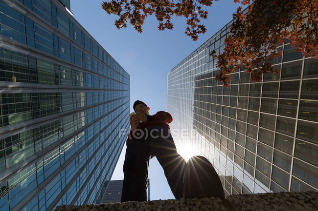 Vista de bajo ángulo del hombre utilizando el teléfono móvil en la ciudad - foto de stock
