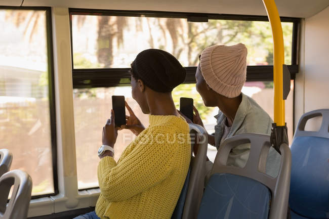 Twins siblings clicking photos with mobile phone in the bus — Stock Photo