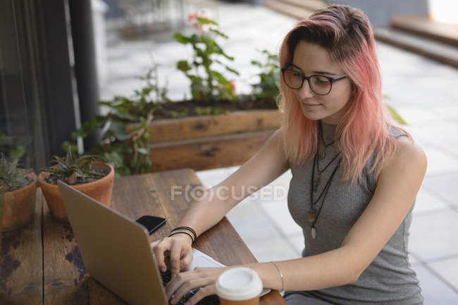 Jeune femme utilisant un ordinateur portable au café — Photo de stock
