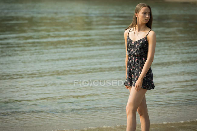 Schöne Frau steht an einem sonnigen Tag am Strand — Stockfoto