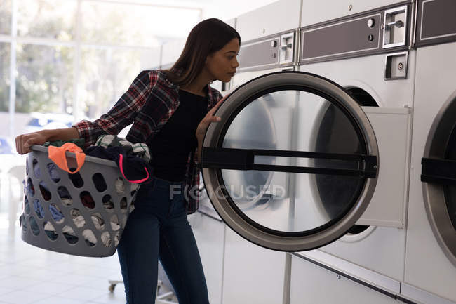 Giovane donna che fa il bucato in lavanderia — Foto stock