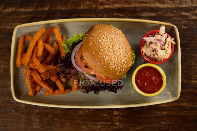 Hambúrguer de carne com batatas fritas servido em mesa de madeira — Fotografia de Stock
