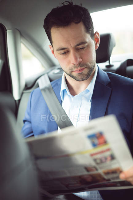 Empresário inteligente lendo jornal em um carro — Fotografia de Stock