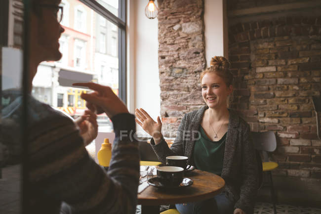 Casal jovem conversando sobre o café no café — Fotografia de Stock