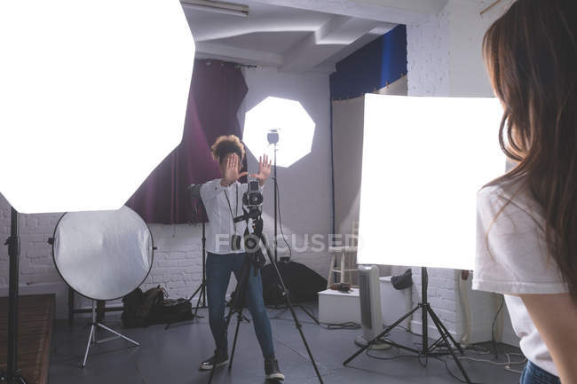Женщина-фотограф щелкает фотографиями модели в фотостудии — стоковое фото