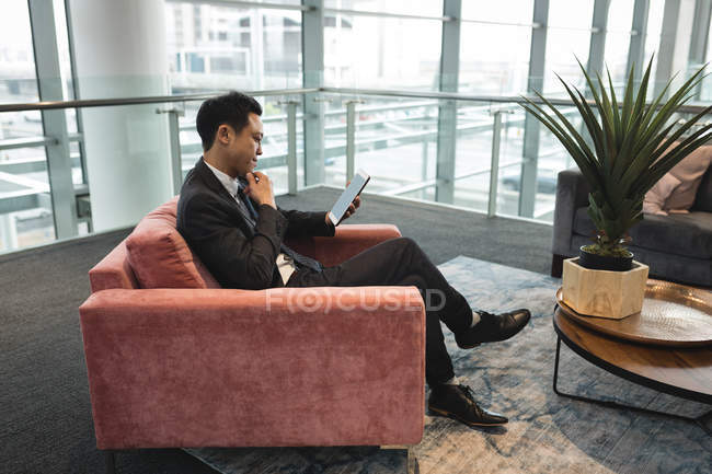 Side view of businessman sitting on chair and using tablet — Stock Photo