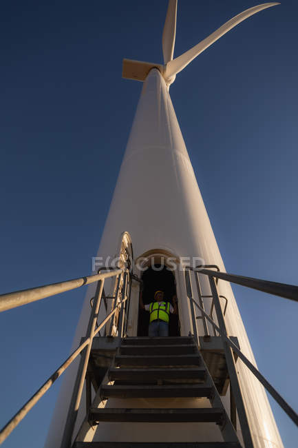 Engenheiro de pé na entrada de um moinho de vento em um parque eólico — Fotografia de Stock
