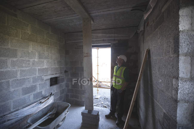Ingeniero mirando el techo en el sitio de construcción - foto de stock