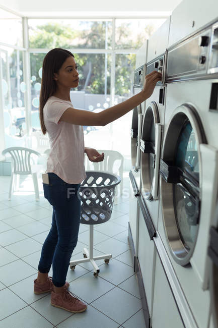 Giovane donna che gestisce la lavatrice in lavanderia — Foto stock