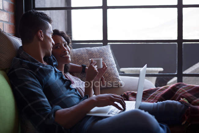 Couple having lemon tea while using laptop in living room at home — Stock Photo