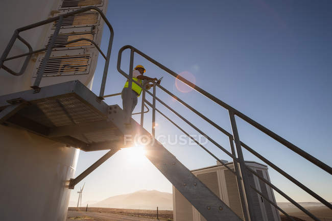 Engenheiro usando um laptop na entrada de um moinho de vento em um parque eólico — Fotografia de Stock