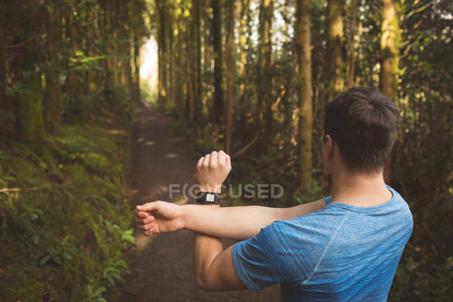 Visão traseira do homem que se estende na floresta — Fotografia de Stock