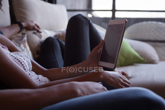 Partie médiane du couple utilisant une tablette numérique dans le salon à la maison — Photo de stock