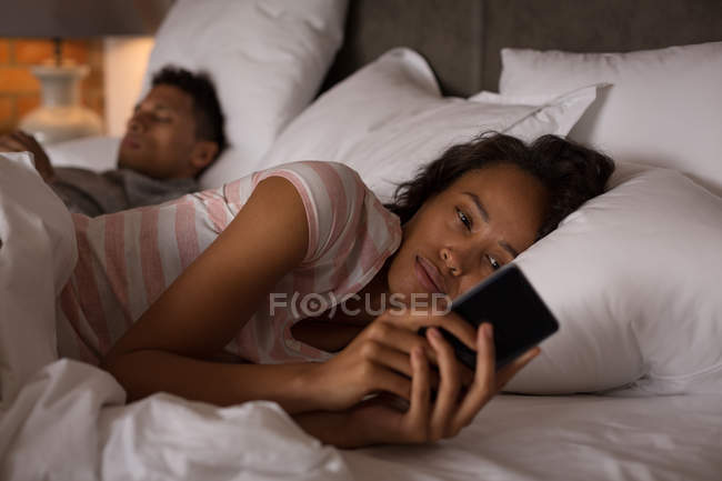 Coppia utilizzando il telefono cellulare in camera da letto a casa — Foto stock