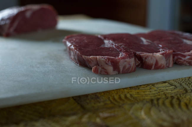 Gros plan sur la viande disposée sur la planche à découper dans la boucherie — Photo de stock