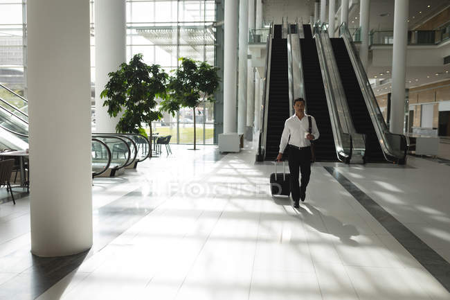 Бизнесмен ходит с чемоданом в офисе — стоковое фото