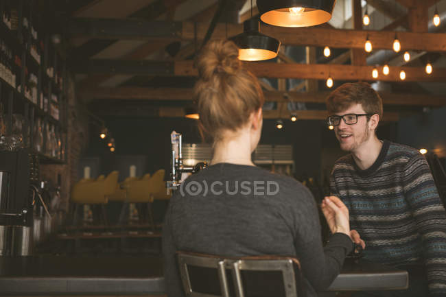 Casal jovem conversando uns com os outros no balcão do bar — Fotografia de Stock
