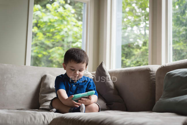 Мальчик пользуется цифровым планшетом в гостиной дома — стоковое фото
