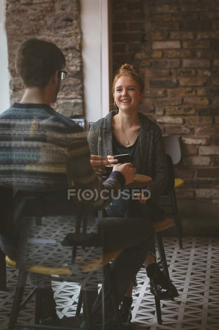 Jeune couple bavardant autour d'un café au café — Photo de stock