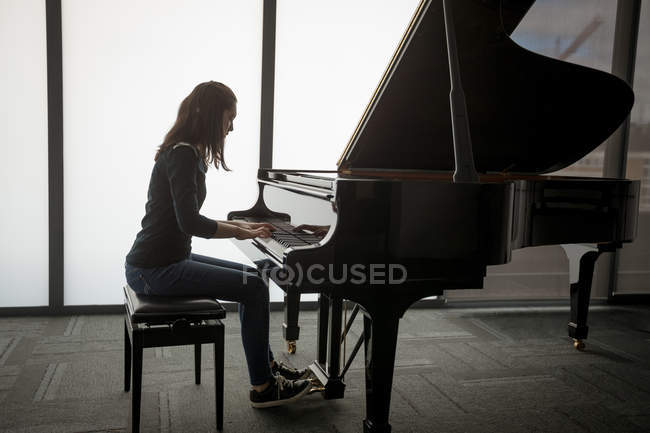 Вид збоку школярка грає на піаніно в музичній школі — стокове фото