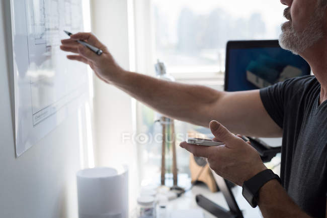 Mid section of man using mobile phone while looking at chart — Stock Photo
