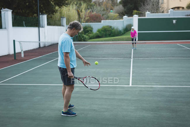 Старшая пара играет в теннис на теннисном корте — стоковое фото