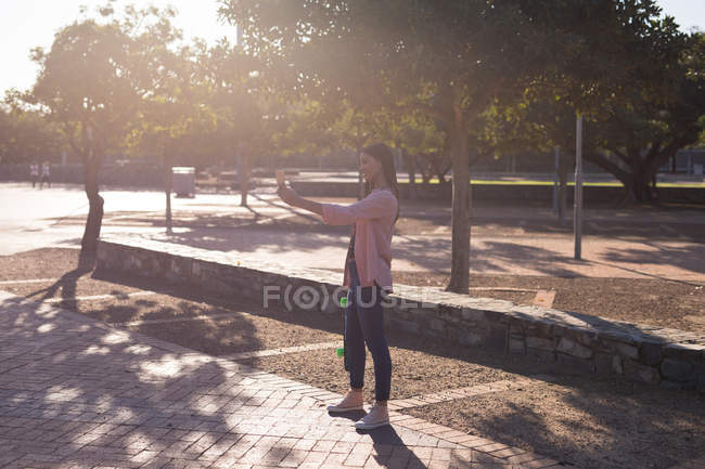 Mulher tirando uma selfie no parque em um dia ensolarado — Fotografia de Stock