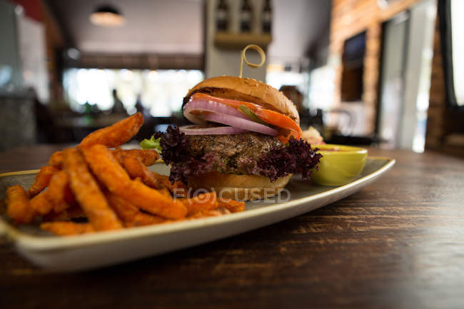 Meat burger with french fries served on wooden table — Stock Photo