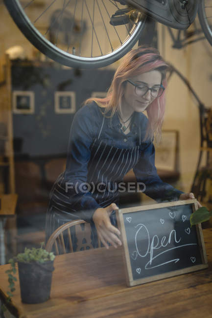 Barista posiziona un cartello aperto sul tavolo della caffetteria — Foto stock