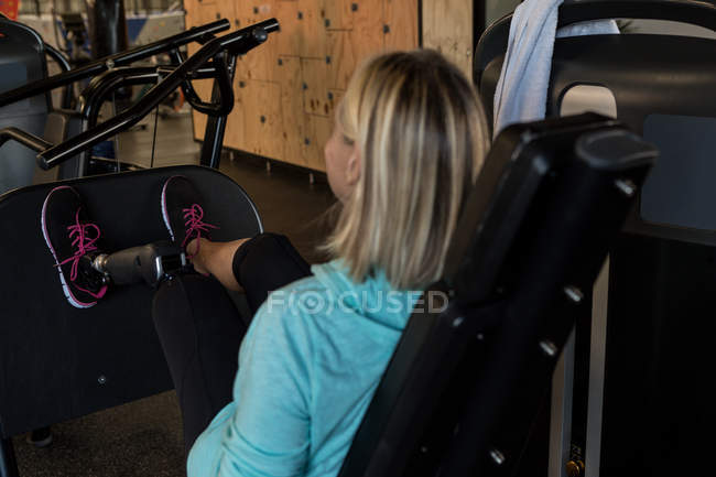 Mulher com deficiência exercitando-se na máquina no ginásio — Fotografia de Stock