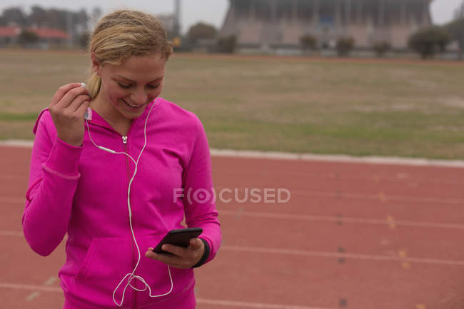 Спортсмен слушает музыку на мобильном телефоне на беговой дорожке — стоковое фото
