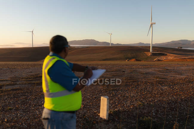Engenheiro tomando notas em um bloco de escrita em um parque eólico — Fotografia de Stock