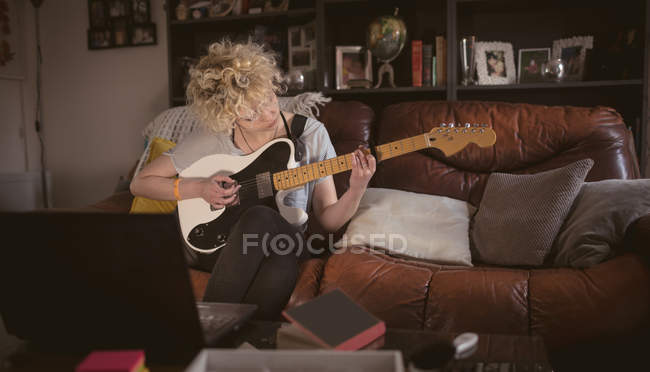 Giovane donna che suona la chitarra in soggiorno a casa — Foto stock