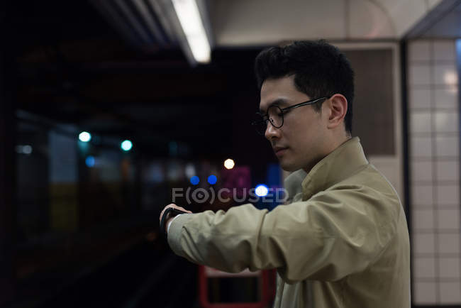Junger Mann kontrolliert Zeit am Bahnhof — Stockfoto