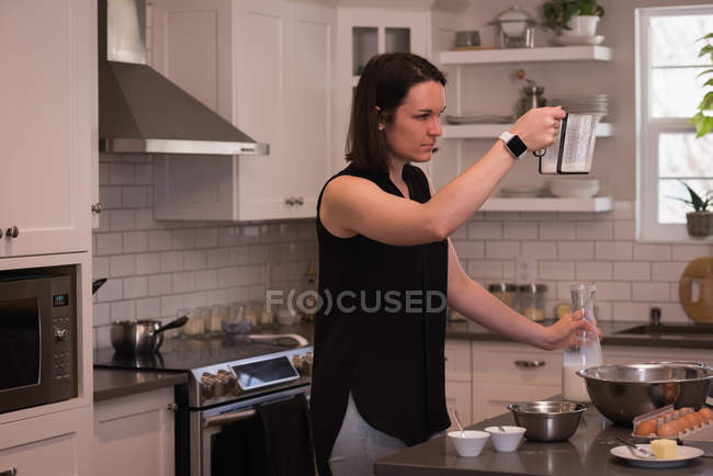 Woman holding jug of milk in kitchen at home — Stock Photo