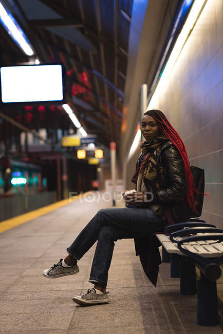 Jeune femme prenant un café à la gare — Photo de stock