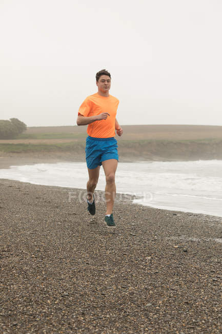 Jeune homme jogging sur la plage — Photo de stock