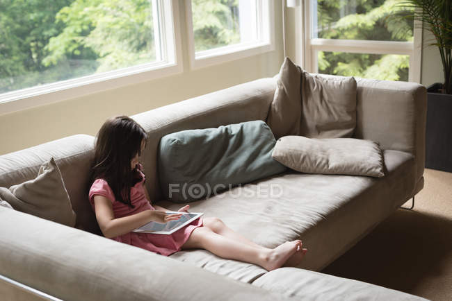 Девушка, использующая цифровой планшет в гостиной дома — стоковое фото