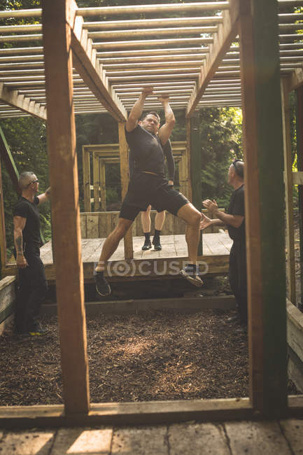 Ajuste homem escalando barras de macaco no acampamento de inicialização — Fotografia de Stock