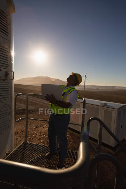 Інженер, який використовує ноутбук біля входу на вітроелектростанцію — стокове фото
