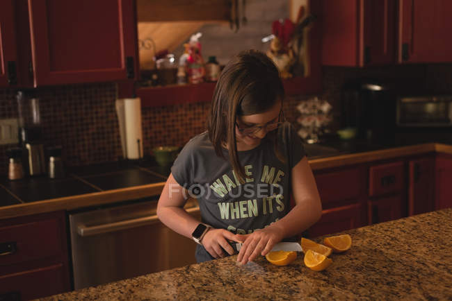 Girl cutting sweet lime in kitchen at home — Stock Photo