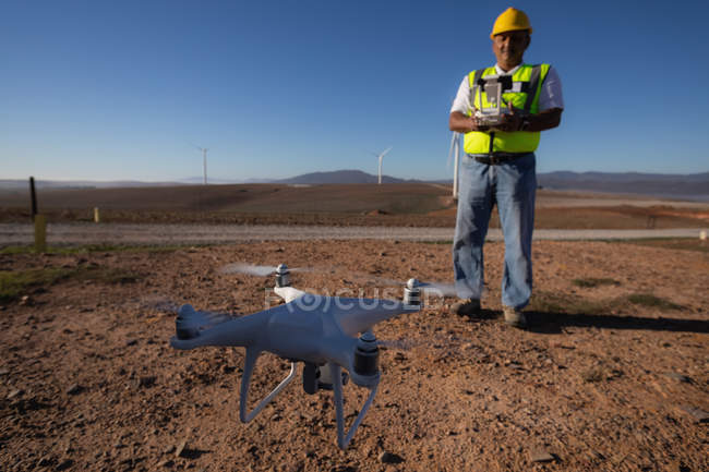 Engenheiro que controla um drone com um controlador num parque eólico — Fotografia de Stock